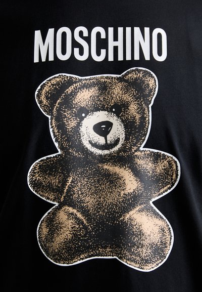 T-shirt noir affichant un grand visuel texturé d'ours en marron avec des détails de son visage et de ses membres. Texte blanc gras "MOSCHINO" au-dessus de l'ours.