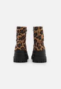 Bottes chevilles en imprimé léopard avec un dessus en tissu doux, une tige effilée et une épaisse semelle en caoutchouc noir. Détail de fermeture à glissière sur le côté visible.