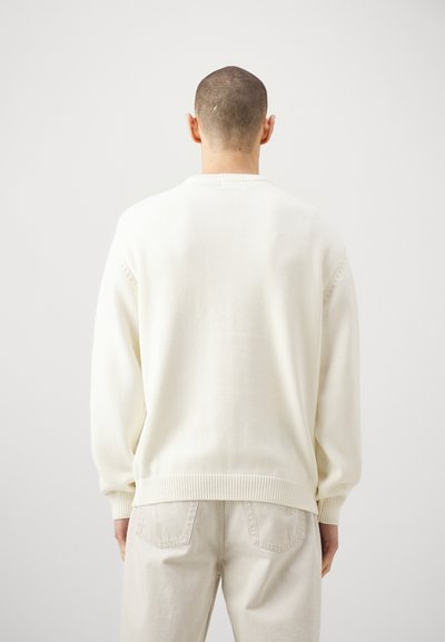 Sweater couleur crème en tricot texturé, doté de manches longues, d'un col rond et d'un ourlet côtelé épais.