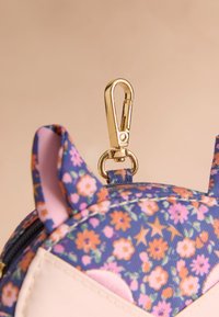 Blommönstrad, lila tygväska med rosa detaljer; guldfärgat metallspänne och beslag; designad med rundade kanter och djuröron.