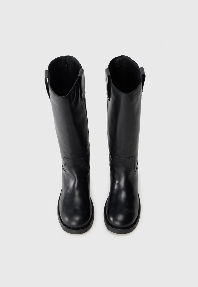 Bottes noires en cuir montantes avec une texture lisse, un bout rond et des anses de tirage en haut. Design simple sans accents matériels visibles.