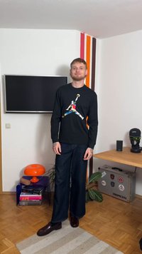 Μαύρο πουκάμισο με μακριά μανίκια που φέρει πολύχρωμο λογότυπο Jumpman, συνδυασμένο με σκούρο τζιν φαρδιάς γραμμής και λαμπερά μαύρα παπούτσια. Πορτοκαλί λάμπα στο φόντο.