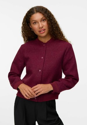 Veste bordeaux à manches longues avec un col rond, des boutons-pression et des poignets côtelés. Fabriquée dans un tissu texturé, conçue pour le confort et la chaleur.