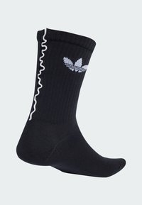 Crne rebraste čarape s bijelim ruffles ukrasom i izvezenim bijelim adidas trefoil logom sa strane.