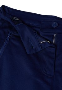 Tmavě modré kalhoty mají zip na zapínání s knoflíkovou sponou, více kapes a hladký textilní povrch. Jsou viditelné ozdobné švy.