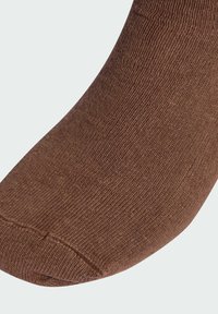 Brązowa bawełniana skarpeta o żebrowanej strukturze, zaokrąglonym nosku i gładkim wykończeniu. Materiał wydaje się miękki i elastyczny.