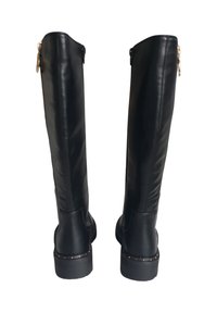Stivali neri al ginocchio realizzati in pelle liscia con suola texturizzata. Presentano una cerniera laterale e borchie decorative attorno alla base.