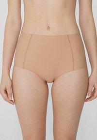 Béžové vysoké kalhotky vyrobené z hladkého materiálu s bezšvým designem a jemnými švy, které poskytují plné pokrytí.