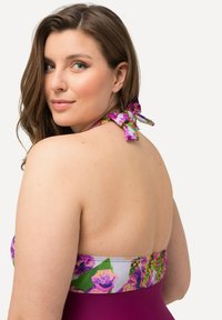 Plavky s květinovým potiskem nahoře, s purpurovými a zelenými akcenty, s uvazováním za krk a jednobarevným burgundským dnem. Hladká textura látky.