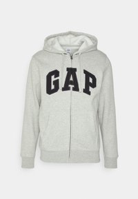 Felpa grigia con zip e cappuccio, che presenta un grande logo nero "GAP" sul davanti, tasche a marsupio e polsini e orlo in costina.