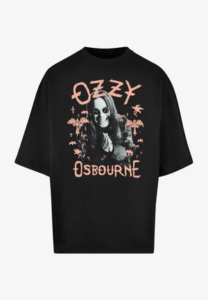 Mustvalge üle mõõtme t-särk, millel on graafiline trükk pikkade juustega figuurist prillidega, ümbritsetud roosa värvi tekstidest ja illustratsioonidest.