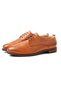 Scarpe in pelle marrone con una texture liscia, punta rotonda e design con lacci. Presentano un tacco basso e una suola scura in contrasto.