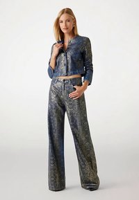 Denim cropped jack en wijde broekspijpen in blauw met metallic slangenprint. Voorzien van een knoopsluiting en een gestructureerd silhouet.