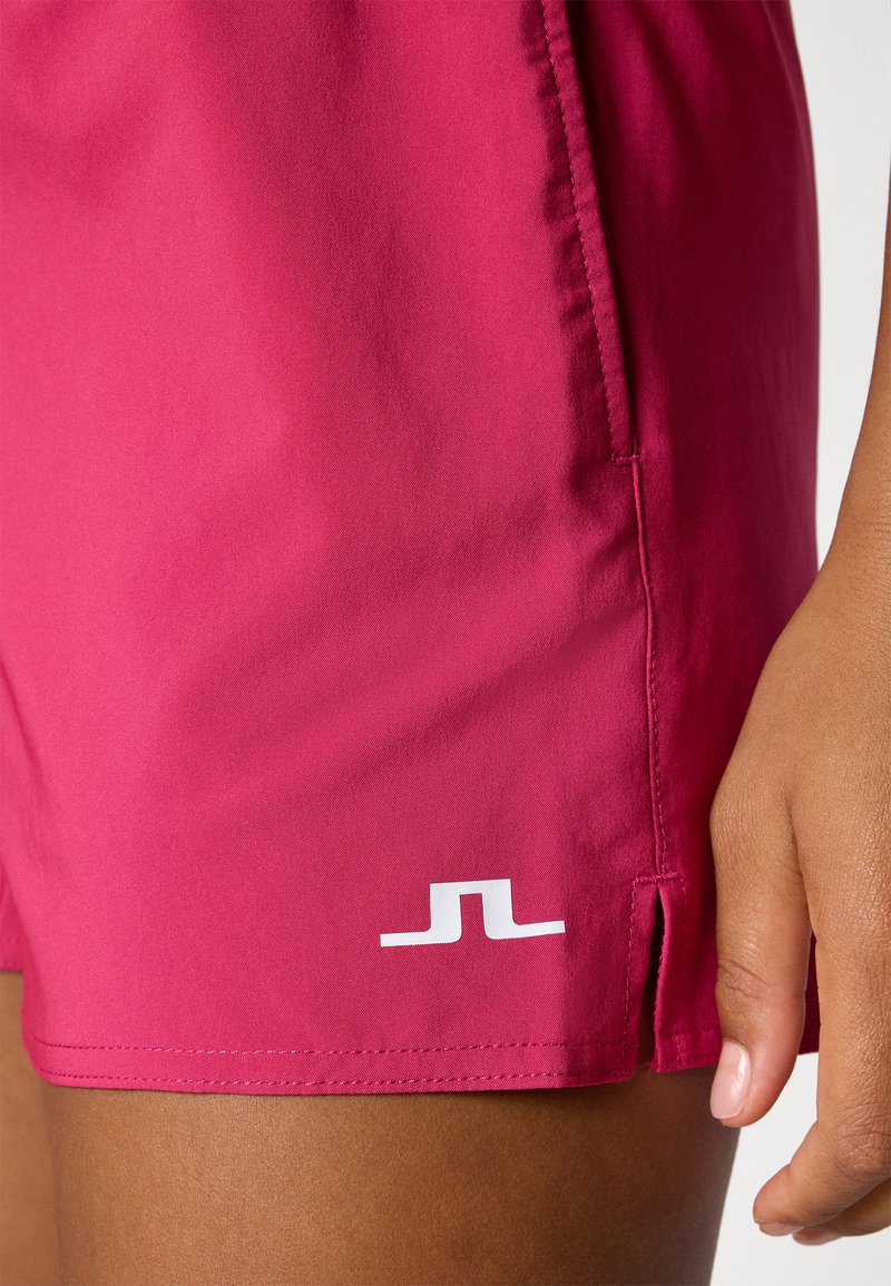 Bañador fucsia fabricado en un material ligero con una textura suave. Presenta un logo blanco en el lado inferior y aberturas laterales para mayor movilidad.