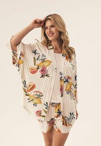 Lekki top w stylu kimono z wzorem kwiatów i owoców w żywych kolorach na kremowym, paskowanym tle, w połączeniu z dopasowanymi szortami.