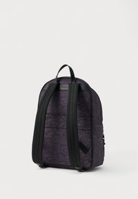 Fioletowy plecak z abstrakcyjnym wzorem, czarnymi wyściełanymi paskami, górnym uchwytem oraz boczną kieszenią na zamek, widok z tyłu na białym tle.