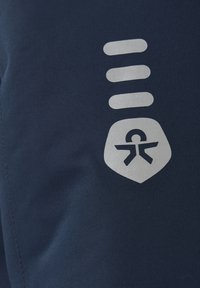 Marinblått tyg med en texturerad finish har en metallisk silverlogotyp och tre horisontella linjer som symboliserar tillgänglighet.