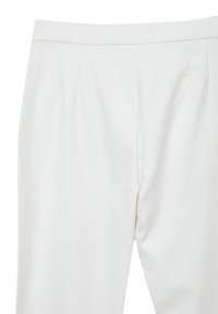 Pantaloni bianchi su misura con pieghe frontali e vita aderente, mostrati dalla vita a metà coscia su uno sfondo semplice.