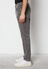 Grijze denim jeans met een slim fit, contrasterende stiksels, vijf zakken en een mid-rise taille. Gecombineerd met witte sportschoenen.