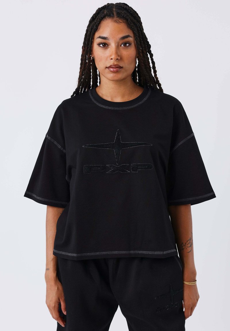 Maglietta nera oversize in cotone con maniche corte, caratterizzata da un logo testurizzato e cuciture a contrasto lungo le cuciture.