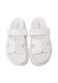 Infradito bianche con due ampie cinghie, materiale morbido, suola piatta e soletta sagomata. Design minimalista con un aspetto pulito e moderno.