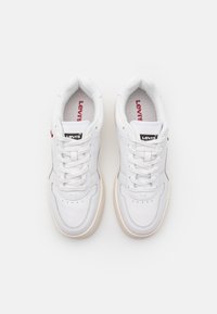 Białe skórzane sneakersy o gładkim wykończeniu, z okrągłym noskiem, białymi sznurówkami i beżową gumową podeszwą. Logo marki widoczne na języku.
