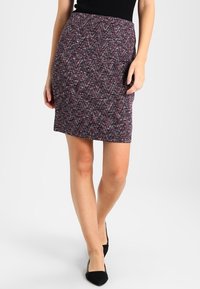 Jupe crayon tissée de couleur violet foncé avec un motif chevron en rouge et blanc. Présente une silhouette ajustée, une texture lisse et une longueur mi-cuisse.