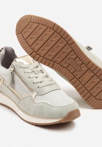 Baskets gris clair avec des matériaux en maille et en daim, fermeture à lacets et fermeture éclair décorative sur le côté ; semelle en caoutchouc avec un motif texturé.