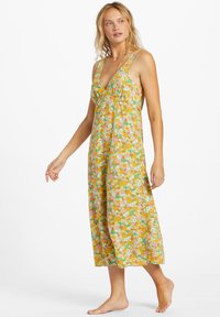 Robe maxi florale avec une base jaune, ornée de fleurs roses, oranges et vertes. Décolleté en V, bretelles larges et tissu fluide.