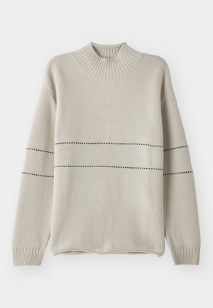 Licht beige gebreide trui met een hoge ribbelkraag, voorzien van zwarte horizontale strepen, lange mouwen en een ontspannen pasvorm.