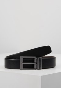 Cintura in pelle nera con fibbia rettangolare opaca. La fibbia presenta un accento argentato con il testo "Porsche Design". Texture liscia su tutta la superficie.