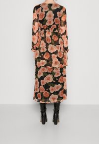 Durchsichtiges Blumenkleid mit langen Ärmeln, das pinke Rosen auf schwarzem Hintergrund zeigt, mit einem taillierten Gürtel, geschichteter Gestaltung, kombiniert mit knielangen schwarzen Stiefeln.