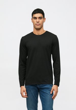 Tricou negru cu mânecă lungă, cu decolteu rotund, croială ajustată și textură moale, asemănătoare cu bumbacul, purtat cu blugi albaștri.