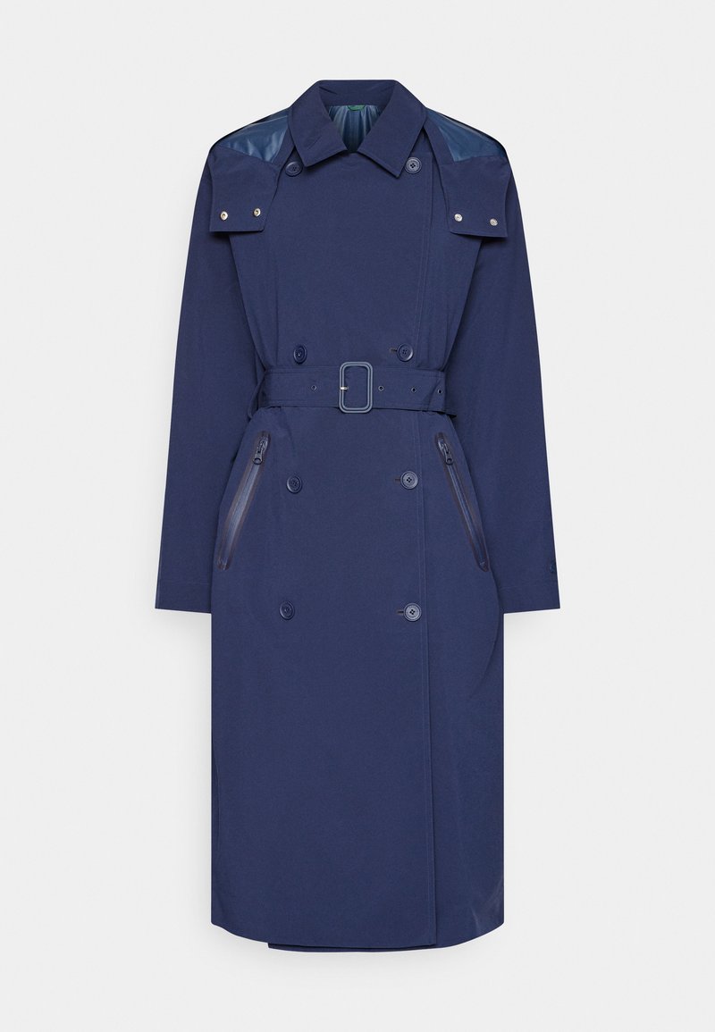Manteau trench navy avec une taille ceinturée, un design croisé et des accents brillants aux épaules. Comprend deux poches zippées et un col.