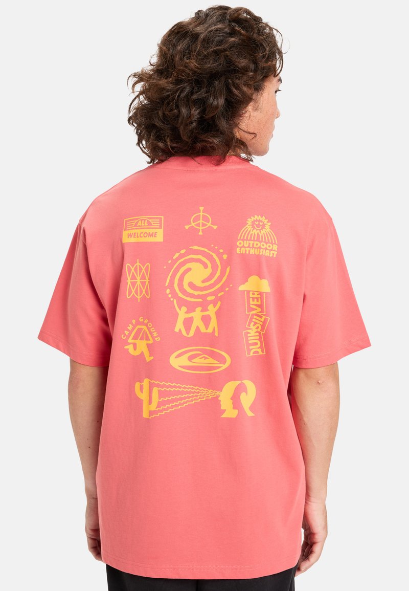Korallrosa t-shirt med korta ärmar, med gula grafiska tryck på baksidan, som inkluderar olika symboler och mönster.