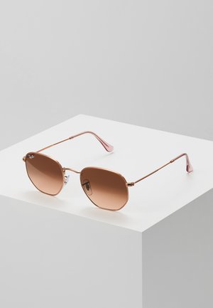 Occhiali da sole in metallo color oro con lenti sfumate marroni e montatura ottagonale. Le asticelle sottili presentano una finitura con dettagli rosa e cuscinetti per il naso.