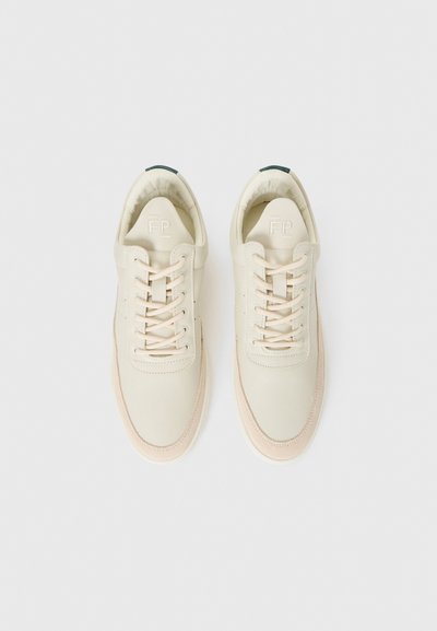 Beige lær sneakers med rund tå, flate snøringer og merket tunge. Har en grønn aksent på hælen og en teksturert såle.