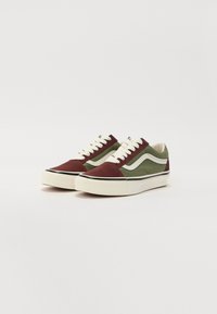Canvas sneakers med ett maroon och grönt färgschema, vita snörningar, gummisulor och sidofält.