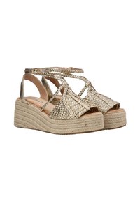 Sandalias de cuña metálicas doradas con correas trenzadas, diseño de punta abierta y suela media envuelta en yute. Correa ajustable en el tobillo para un ajuste seguro.