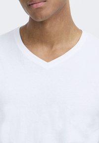 White V-neck t-shirt made of soft cotton fabric; features a smooth texture and lightweight design with a classic silhouette.