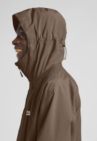 Giacca impermeabile marrone con cappuccio, dotata di chiusura con zip e cordoncino regolabile. Tessuto leggero, texture liscia e design minimalista.