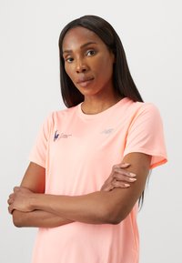 T-shirt de sport léger, évacuant l'humidité, à manches courtes, de couleur rose vif avec une texture en maille, arborant les logos du Marathon de New York et de New Balance.