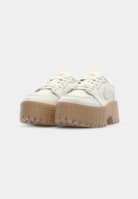 Hvide lædersneakers med en tyk, struktureret tan gummisåle, der har et lavprofil-design, rund tå og snørelukning.