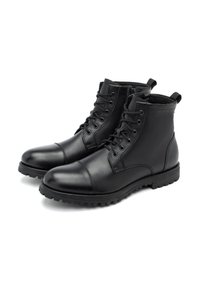 Botas de tobillo de cuero negro con un acabado suave, cordones en la parte delantera, punta redonda y suela resistente para tracción. Incluyen lengüetas en la parte posterior.