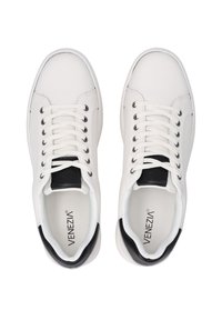 Białe sneakersy z gładką skórzaną cholewką, czarnymi akcentami na pięcie oraz czarnymi sznurowadłami. Wyróżniają się logo na języku oraz okrągłym wzorem noska.