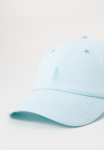 Lyseblå bomullskaps med buet skjerm, med et brodert logo på fronten og ventilasjonsøyelopper på toppen.