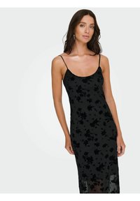 Svart kjole med blomstertrykk, tynne spaghetti-stropper, en tettsittende silhuett og gjennomsiktig lag nederst. Jevn tekstur over hele kjolen.