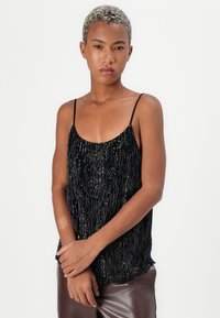 Musthave must värviline topp, millel on tikitud disain ja ääris, õhukesed õlapaelad ja mugav lõige.