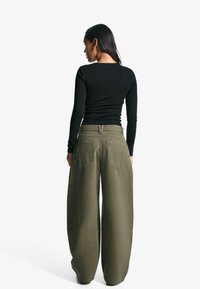 Black long-sleeve shirt and olive green wide-leg pants with back pockets, made from soft fabric. The outfit has a relaxed fit.