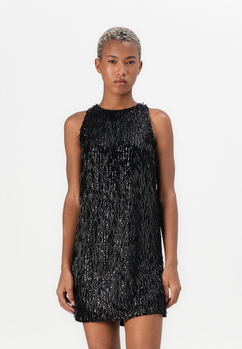 Schwarzes ärmelloses Kleid mit einem strukturierten Fransen-Design, mit einem figurbetonten Oberteil und einem lockeren Saum, der Dimension und Bewegung verleiht.